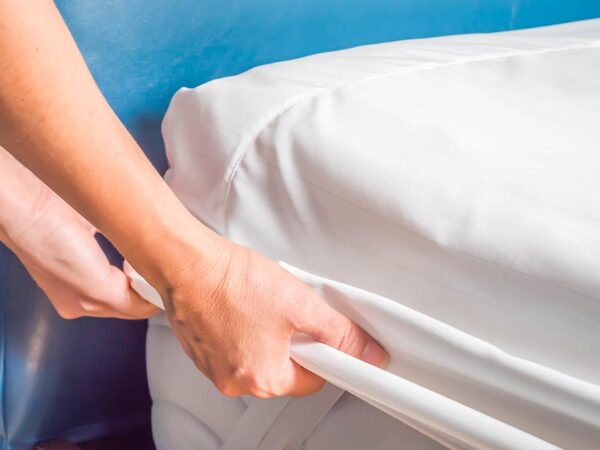 Woman is putting the bedding cover or mattress pad on the bed or putting off for cleaning process.